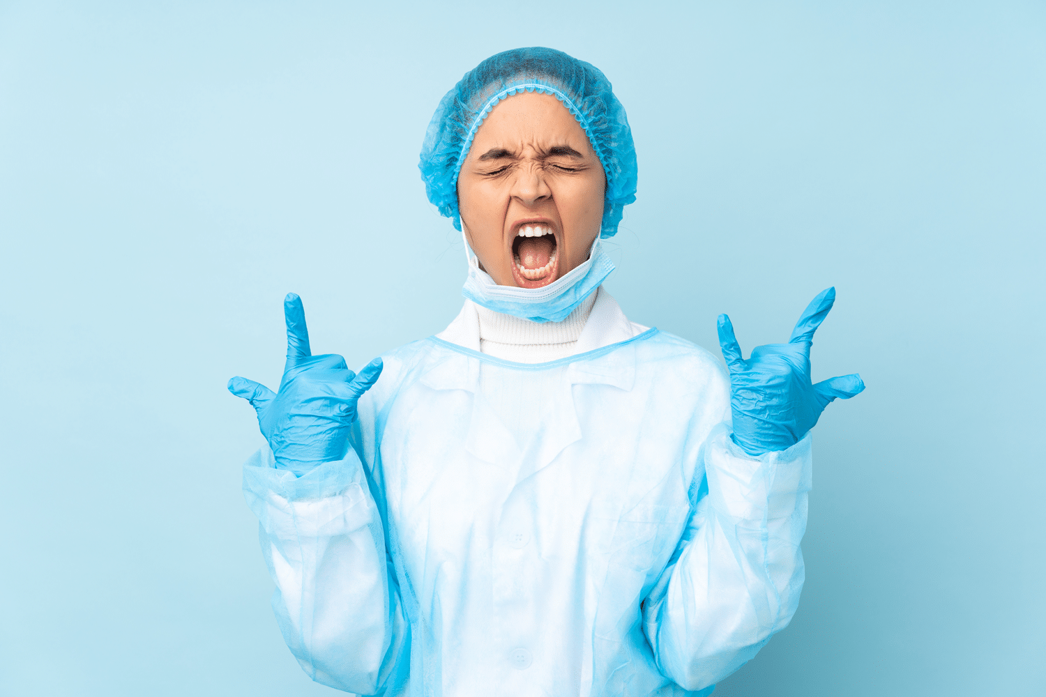 Female surgeon in scrubs making a rock and roll hand gesture